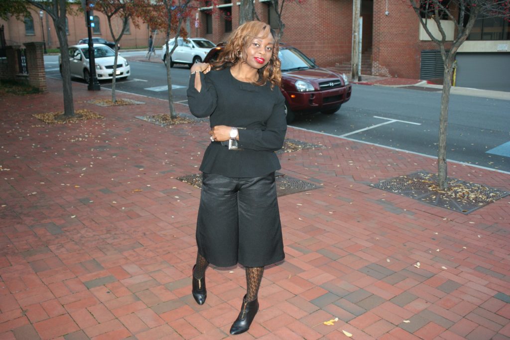 Black culottes with black peplum top, black patterned tights and black boots