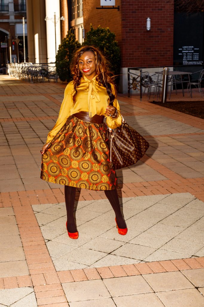 Gold and orange print midi circle skirt with gold tie neck blouse