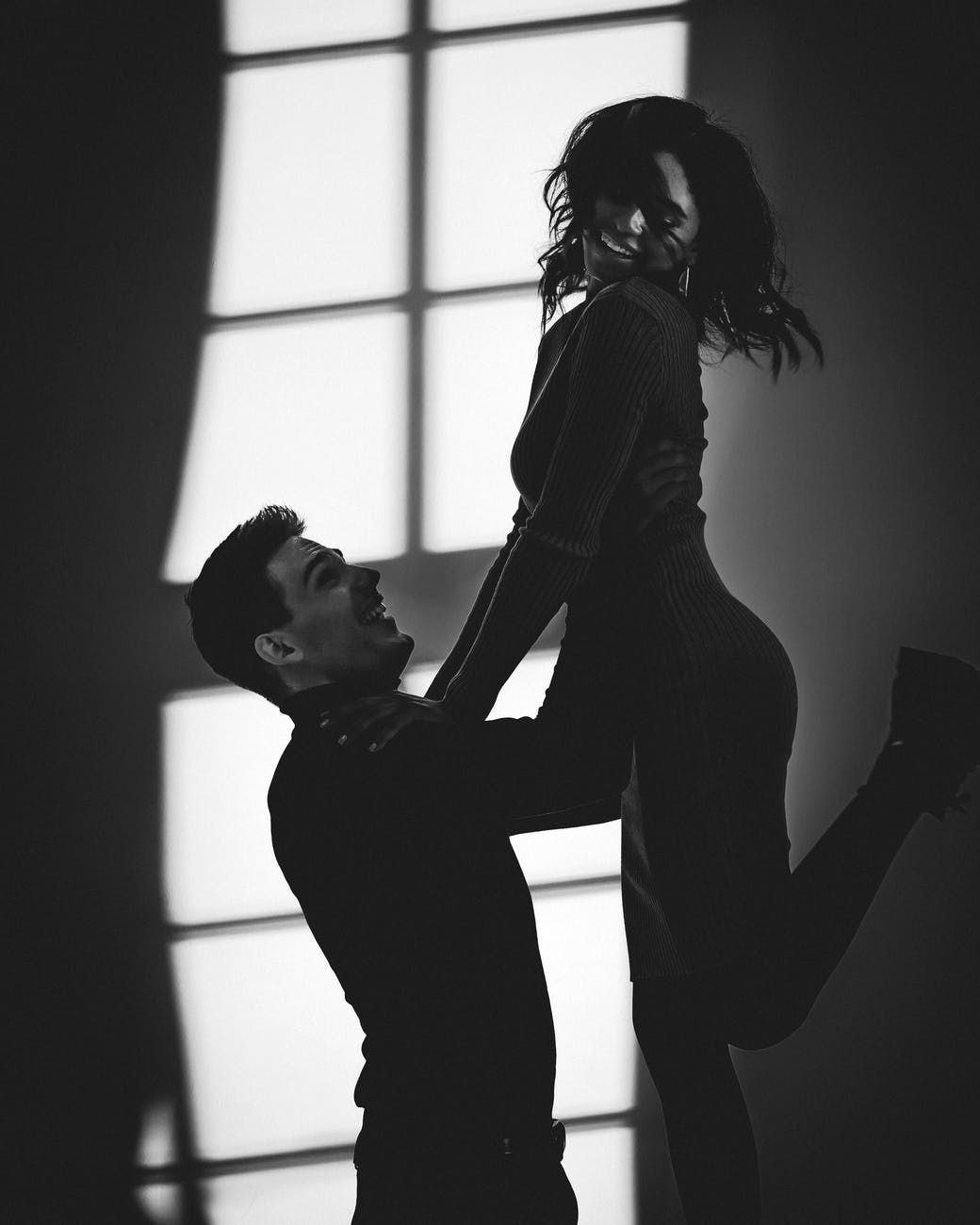 grayscale photography of man lifting woman