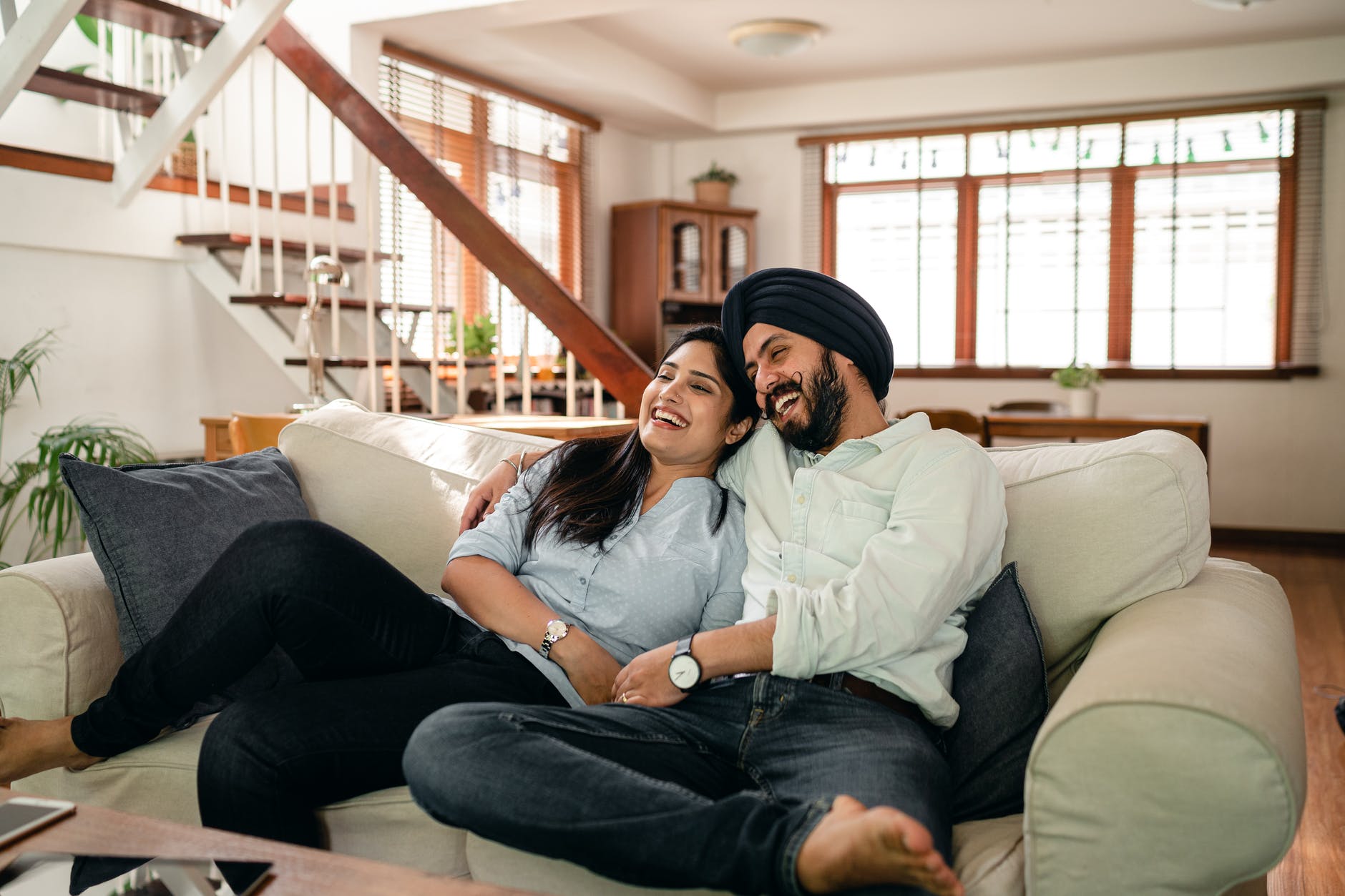 happy Indian couple laughing and watching a movie at home