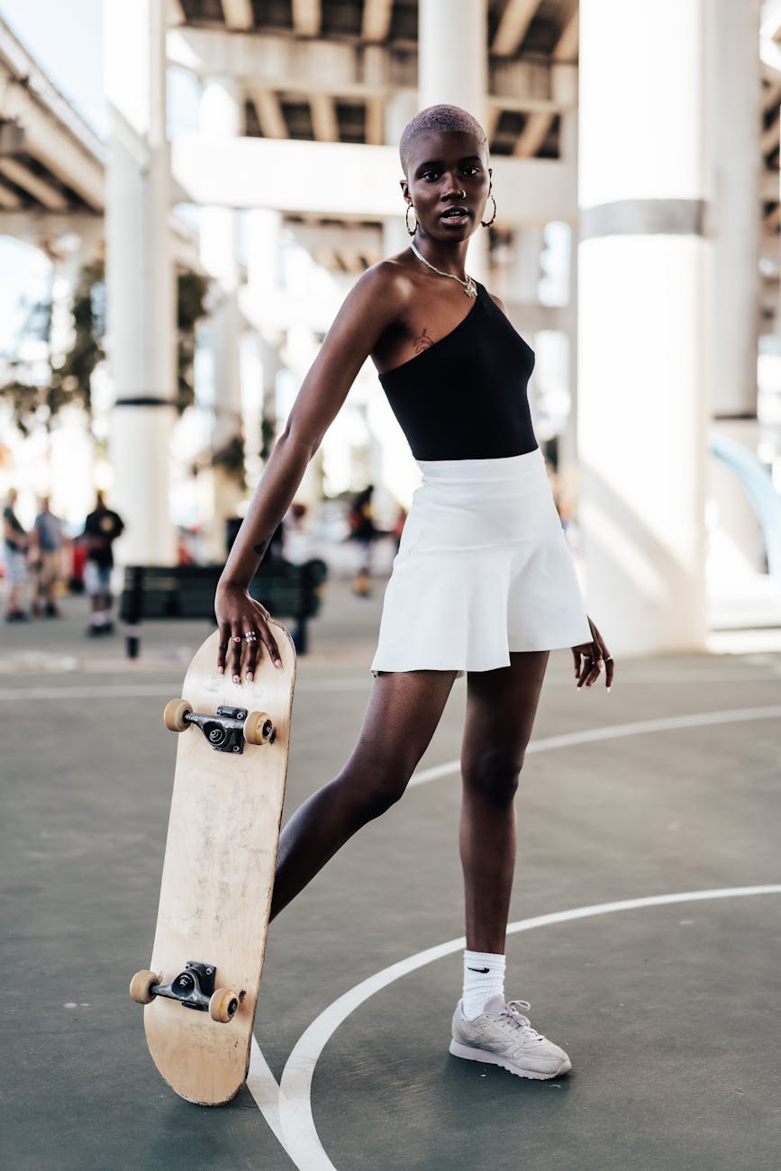 woman in tennis skirt holding skateboard